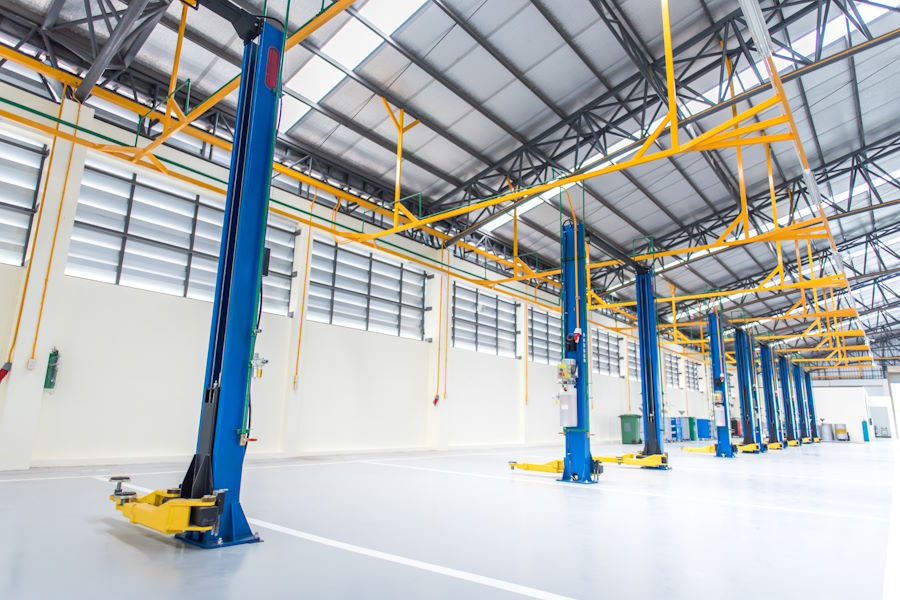 The interior decoration is an epoxy floor of an industrial building or a large automobile repair center with a steel roof structure that is built in an industrial factory.