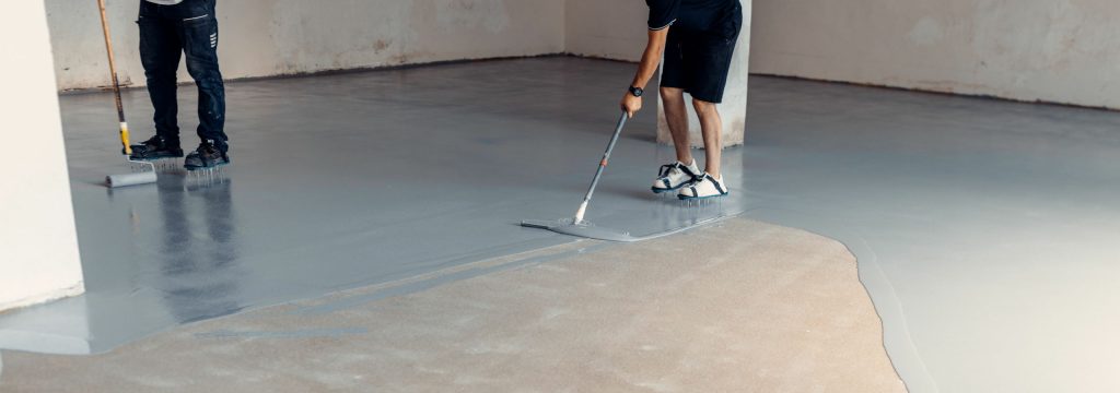 Construction workers applying grey epoxy resin in an industrial